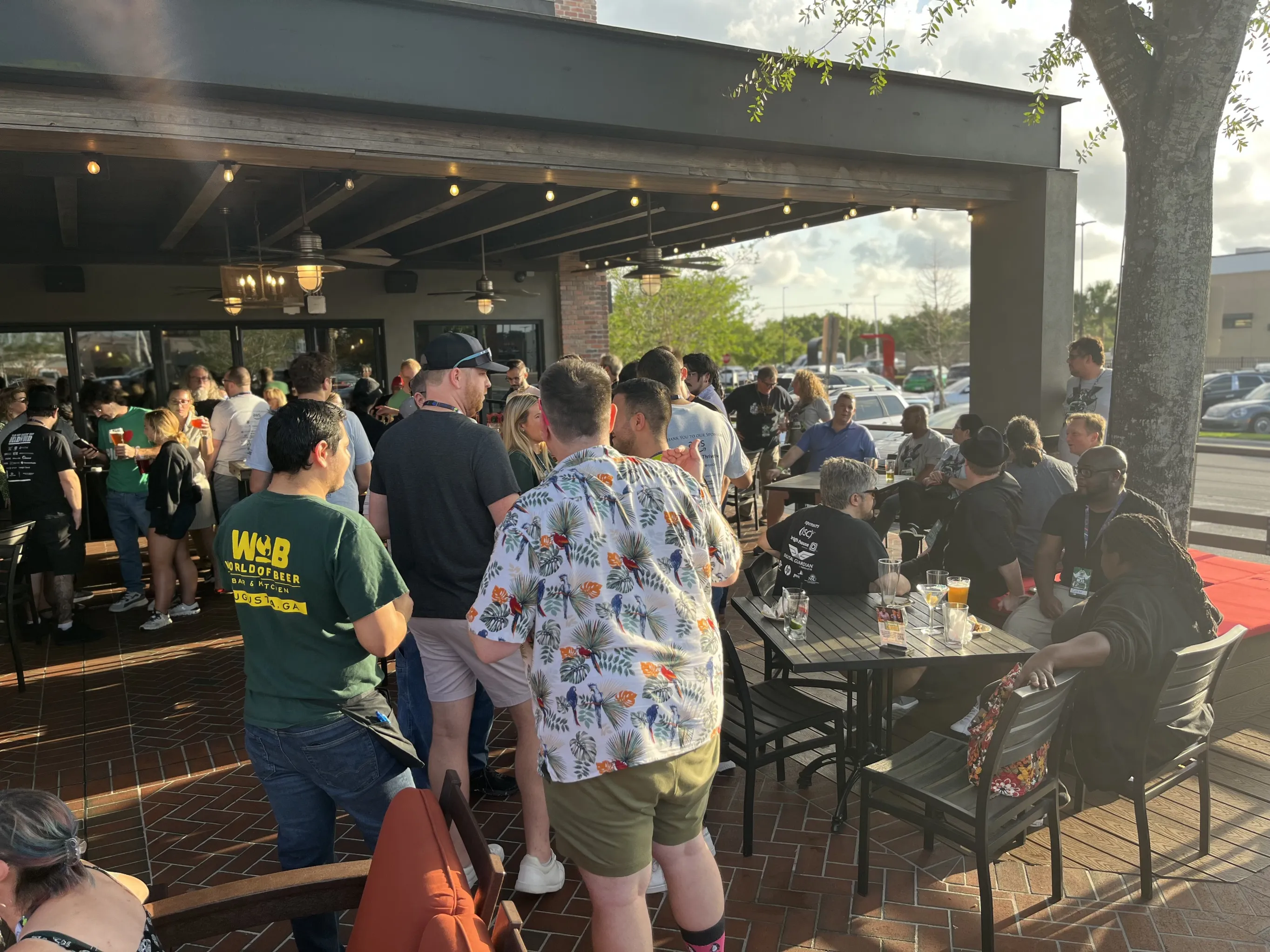 A crowd of BSides Tampa participants mingling at the outdoor Happy Hour